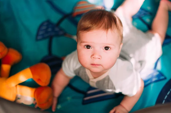 Cute little baby boy playing in colorful playpen, indoors. Beautiful child having fun at nursery. — Stock Photo, Image