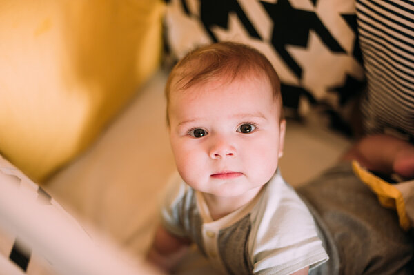 Close-up portrait of a cheerful cute baby in the crib at home