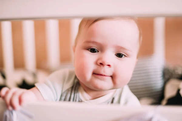 Retrato de cerca de un lindo bebé alegre en la cuna en casa —  Fotos de Stock