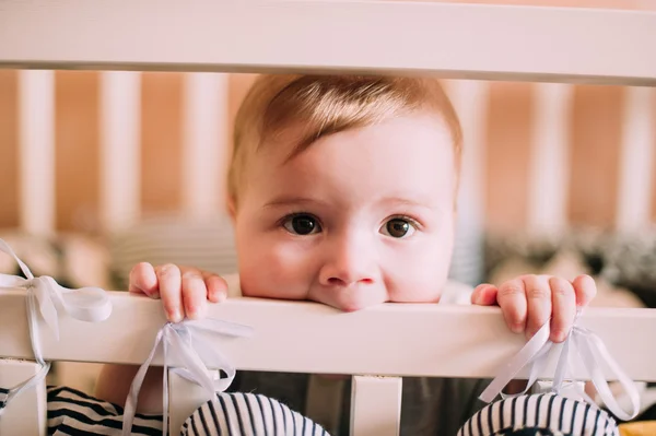 Retrato de cerca de un lindo bebé alegre en la cuna en casa —  Fotos de Stock