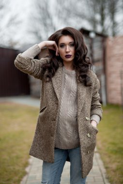 Bahar country tarzında. Beyaz örgü kazak ve kürklü şapka ayakta house, giyen kazak rahat yakınındaki bahçedeki rustik ahşap duvar önünde genç kadın portresi tam uzunlukta.