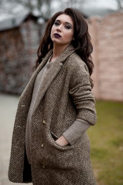 Bahar country tarzında. Beyaz örgü kazak ve kürklü şapka ayakta house, giyen kazak rahat yakınındaki bahçedeki rustik ahşap duvar önünde genç kadın portresi tam uzunlukta.