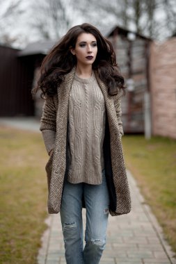 Bahar country tarzında. Beyaz örgü kazak ve kürklü şapka ayakta house, giyen kazak rahat yakınındaki bahçedeki rustik ahşap duvar önünde genç kadın portresi tam uzunlukta.