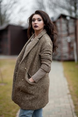 Bahar country tarzında. Beyaz örgü kazak ve kürklü şapka ayakta house, giyen kazak rahat yakınındaki bahçedeki rustik ahşap duvar önünde genç kadın portresi tam uzunlukta.