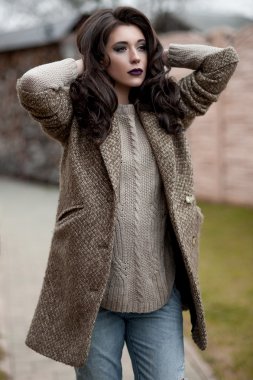 Bahar country tarzında. Beyaz örgü kazak ve kürklü şapka ayakta house, giyen kazak rahat yakınındaki bahçedeki rustik ahşap duvar önünde genç kadın portresi tam uzunlukta.