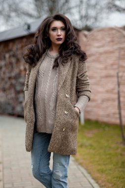 Bahar country tarzında. Beyaz örgü kazak ve kürklü şapka ayakta house, giyen kazak rahat yakınındaki bahçedeki rustik ahşap duvar önünde genç kadın portresi tam uzunlukta.