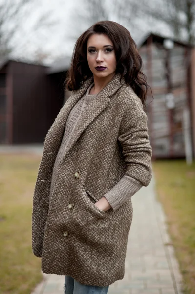 Bahar country tarzında. Beyaz örgü kazak ve kürklü şapka ayakta house, giyen kazak rahat yakınındaki bahçedeki rustik ahşap duvar önünde genç kadın portresi tam uzunlukta.