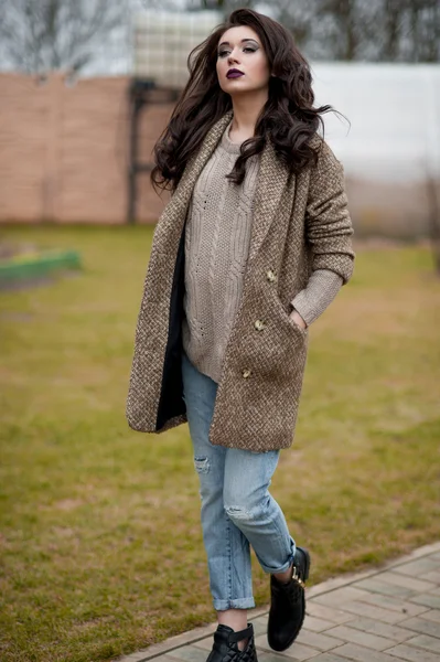 Bahar country tarzında. Beyaz örgü kazak ve kürklü şapka ayakta house, giyen kazak rahat yakınındaki bahçedeki rustik ahşap duvar önünde genç kadın portresi tam uzunlukta.