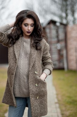 Bahar country tarzında. Beyaz örgü kazak ve kürklü şapka ayakta house, giyen kazak rahat yakınındaki bahçedeki rustik ahşap duvar önünde genç kadın portresi tam uzunlukta.