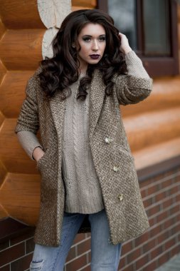 Bahar country tarzında. Beyaz örgü kazak ve kürklü şapka ayakta house, giyen kazak rahat yakınındaki bahçedeki rustik ahşap duvar önünde genç kadın portresi tam uzunlukta.