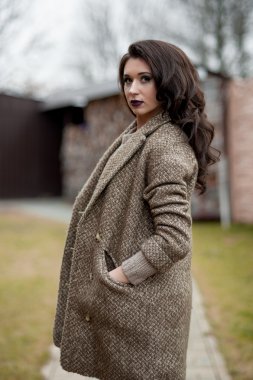 Bahar country tarzında. Beyaz örgü kazak ve kürklü şapka ayakta house, giyen kazak rahat yakınındaki bahçedeki rustik ahşap duvar önünde genç kadın portresi tam uzunlukta.