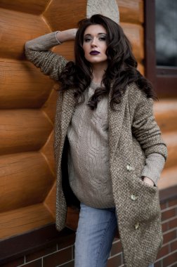 Bahar country tarzında. Beyaz örgü kazak ve kürklü şapka ayakta house, giyen kazak rahat yakınındaki bahçedeki rustik ahşap duvar önünde genç kadın portresi tam uzunlukta.