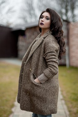 Bahar country tarzında. Beyaz örgü kazak ve kürklü şapka ayakta house, giyen kazak rahat yakınındaki bahçedeki rustik ahşap duvar önünde genç kadın portresi tam uzunlukta.