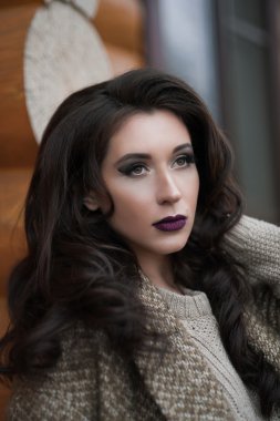 Bahar country tarzında. Beyaz örgü kazak ve kürklü şapka ayakta house, giyen kazak rahat yakınındaki bahçedeki rustik ahşap duvar önünde genç kadın portresi tam uzunlukta.