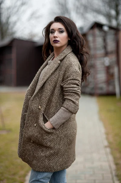 Bahar country tarzında. Beyaz örgü kazak ve kürklü şapka ayakta house, giyen kazak rahat yakınındaki bahçedeki rustik ahşap duvar önünde genç kadın portresi tam uzunlukta.