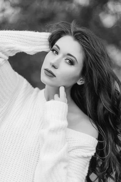 Hermosa mujer de moda en un sombrero negro y abrigo blanco posando al aire libre — Foto de Stock