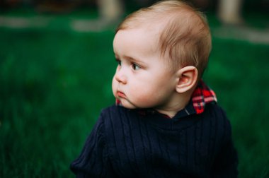 Yeşil otlar arasında Bahar çimenlerin üzerine oturmuş bir güzel bebek