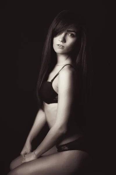 Shot van een sexy vrouw in zwarte lingerie op zwarte achtergrond. — Stockfoto