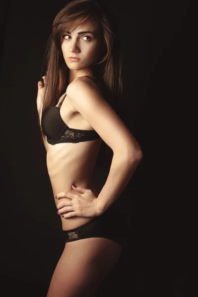 Shot van een sexy vrouw in zwarte lingerie op zwarte achtergrond. — Stockfoto