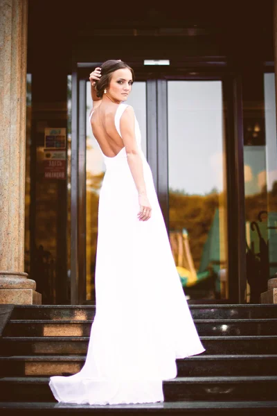 Krásná sexy bruneta nevěsta v bílých šatech, chůzi do schodů — Stock fotografie