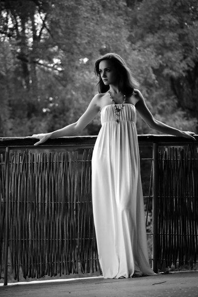 Beautiful woman. Young pretty woman wearing a white dress in a park outdoors. Spring and summer natural beauty concept.