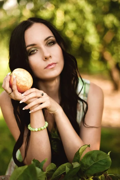 Жінка в барвистій сукні максі з коробкою з яблуками в сонячному одязі — стокове фото