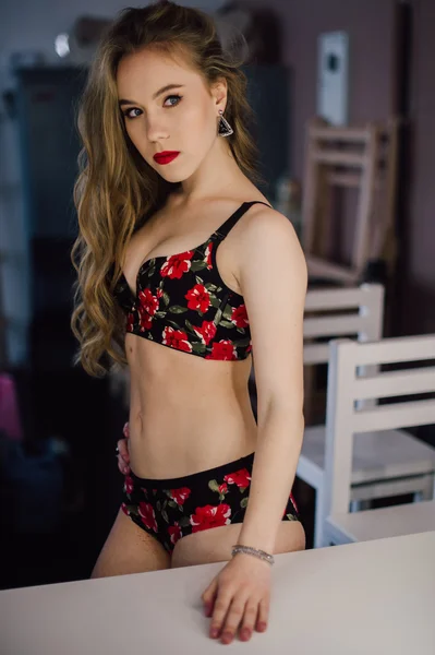 Joven hermosa mujer aplicando su maquillaje cara con cepillo, mirando en un espejo, sentado en la silla en el vestidor con espejo vintage habitación oscura, usando lencería roja — Foto de Stock