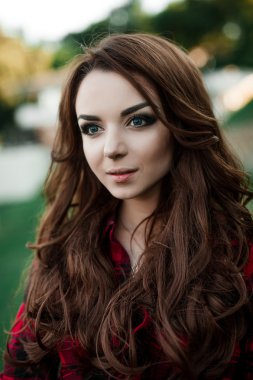 Poz ve kentsel duvar arka planda kırmızı kareli gömlek, şort, açık havada yaz portre yakınındaki gülümseyen güzel genç hippi kız.