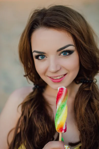 Férias de verão, viagens, turismo, junk food e conceito de pessoas - jovem mulher de óculos de sol comendo sorvete colorido no fundo da praia resort, vestindo maiô amarelo — Fotografia de Stock