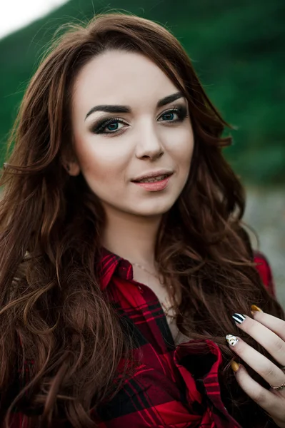 Bella giovane ragazza hipster posa e sorridente vicino al muro urbano sfondo in camicia a quadri rossa, pantaloncini, all'aperto ritratto estivo . — Foto Stock