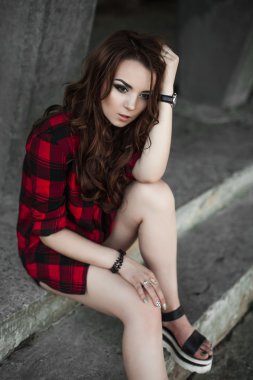 Poz ve kentsel duvar arka planda kırmızı kareli gömlek, şort, açık havada yaz portre yakınındaki gülümseyen güzel genç hippi kız.