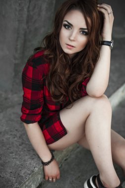 Poz ve kentsel duvar arka planda kırmızı kareli gömlek, şort, açık havada yaz portre yakınındaki gülümseyen güzel genç hippi kız.