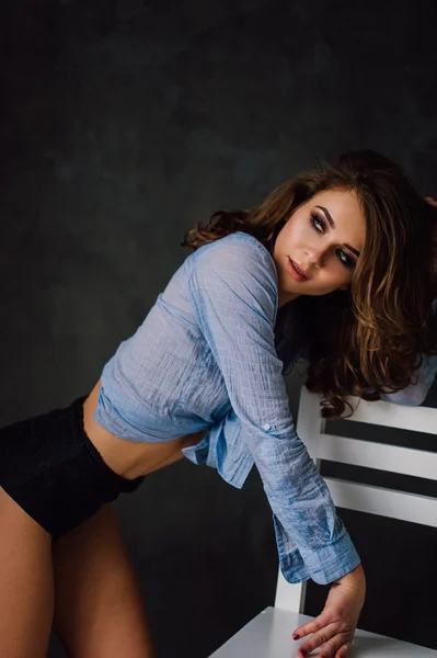 Portrait of sexy young positive woman posing in studio at natural light, wearing blue shirt, has good and healthy fit. Studio retouched shot. — Stock Photo, Image