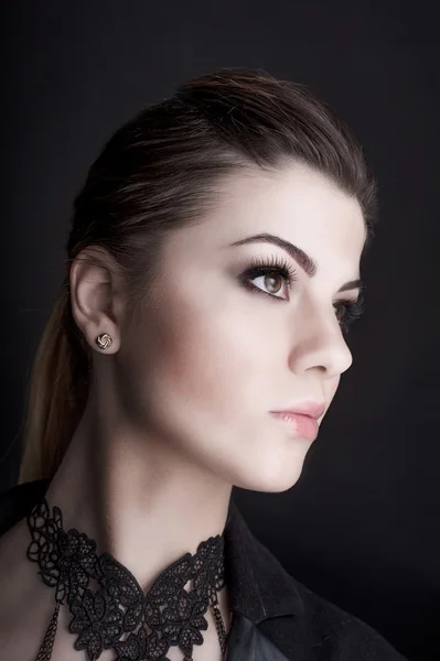 Hermosa mujer con maquillaje profesional con chaqueta sobre fondo oscuro. Peinado, filmado en estudio — Foto de Stock