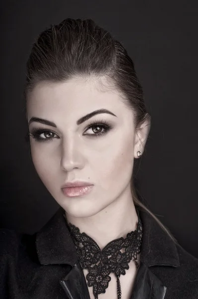 Mooie vrouw met professionele make-up dragen jas over donkere achtergrond. Kapsel, Studio schot — Stockfoto