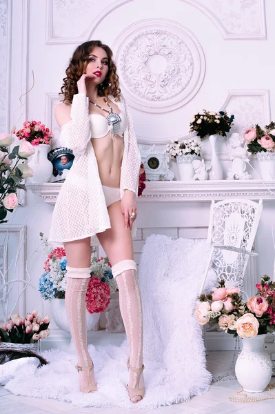 Mooie jonge sexy vrouw, het dragen van witte lingerie, kamer versierd met bloemen. Perfecte make-up. Beauty Beli parfum mode. Wimpers. Studio geretoucheerd schot. — Stockfoto