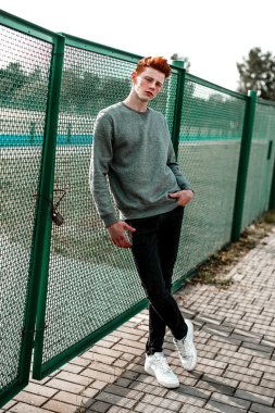 Casual giyim güneşli bir günde açık, stadium yanında duran bir genç yakışıklı kırmızı saçlı moda çocuk