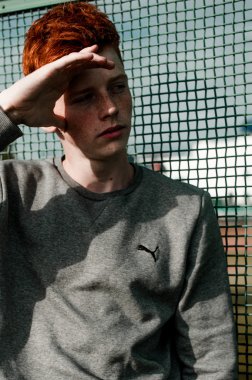 Casual giyim güneşli bir günde açık, stadium yanında duran bir genç yakışıklı kırmızı saçlı moda çocuk