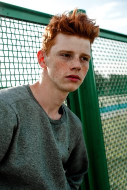 Casual giyim güneşli bir günde açık, stadium yanında duran bir genç yakışıklı kırmızı saçlı moda çocuk