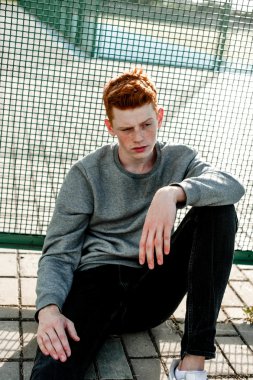 Casual giyim güneşli bir günde açık, stadium yanında duran bir genç yakışıklı kırmızı saçlı moda çocuk