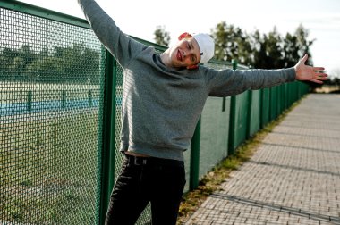 Casual giyim güneşli bir günde açık, stadium yanında duran bir genç yakışıklı kırmızı saçlı moda çocuk