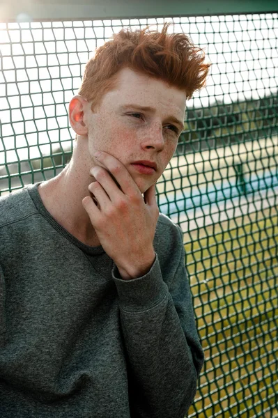 한 젊은 잘생긴 빨간 머리 유행 소년 화창한 날 야외, 경기장 근처 서 캐주얼 옷을 입고 — 스톡 사진