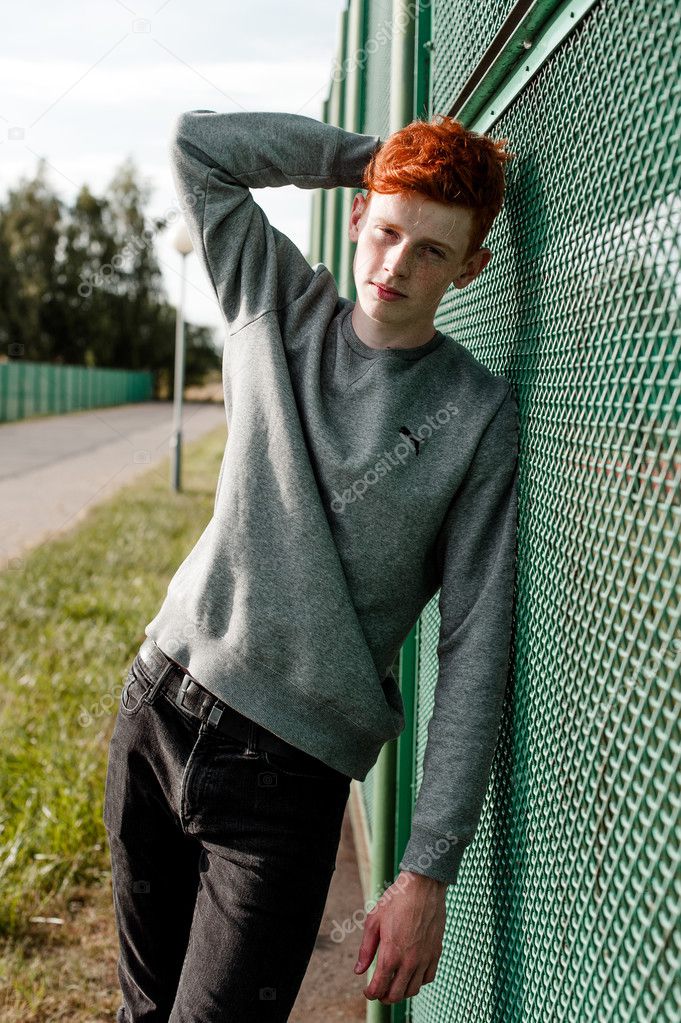 Un joven guapo pelirrojo chico de moda de pie cerca del estadio en