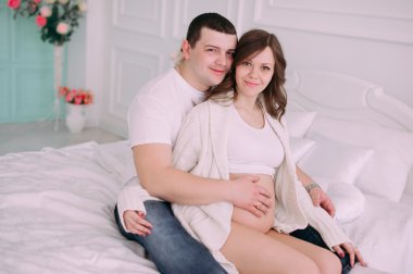 Bebeğin doğumu için bekleyen ailen. Hamile bir kadın ve kocası giyen beyaz giyim