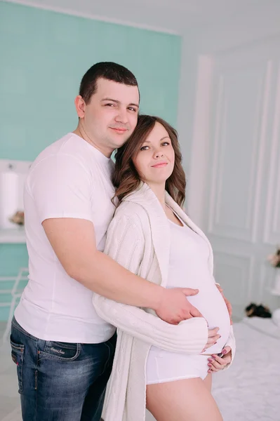 Família à espera do nascimento do bebé. Uma mulher grávida e seu marido vestindo roupas brancas — Fotografia de Stock