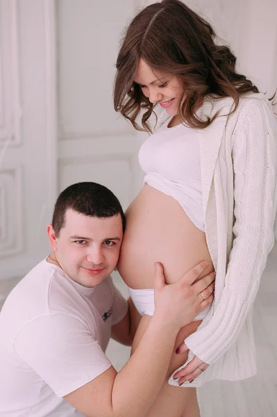 Família à espera do nascimento do bebé. Uma mulher grávida e seu marido vestindo roupas brancas — Fotografia de Stock