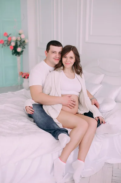 Familia esperando el nacimiento del bebé. Una mujer embarazada y su marido con ropa blanca — Foto de Stock