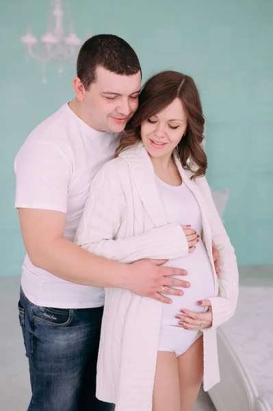 Familia esperando el nacimiento del bebé. Una mujer embarazada y su marido con ropa blanca — Foto de Stock