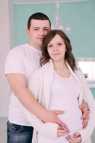 Familia esperando el nacimiento del bebé. Una mujer embarazada y su marido con ropa blanca — Foto de Stock