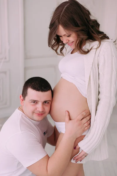 Familia esperando el nacimiento del bebé. Una mujer embarazada y su marido con ropa blanca — Foto de Stock